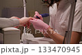 Manicure process. Polygel technique. Female beautician hands in gloves holding clients nail fingers using automatic electric equipment for gel procedure. 133470945