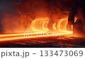Sheet metal rolling machine pressing glowing hot metal under orange light 133473069