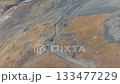 Aerial view of rugged terrain with winding road, camera pans across landscape 133477229