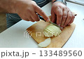 Male hands carefully slice onion with a knife on a wooden cutting board home kitchen cooking process top view culinary b roll video 133489560