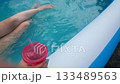 POV poolside break hand with cup and legs in blue water camera movement light clip for stories beverage brand lifestyle b roll home vacation staycation 133489563