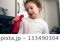 Little girl examining and eating red pepper in home kitchen 133490304