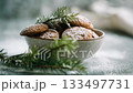 A rustic bowl of gingerbread cookie covered with powdered sugar and pine twig decoration on linen fabric in warm natural light 133497731