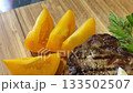 yellow tomato slices and entrecote beef steaksauce to traditional ossobuco dish at wooden table, closeup 133502507