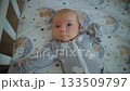 An infant lies in a crib and looks at a mobile that spins above its bed 133509797
