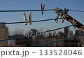 Clothespins hanging on a clothesline against a clear blue sky. The background features blurred buildings, creating an urban atmosphere. 133528046