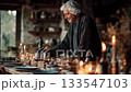 An elderly man pouring red wine at a festive candlelit dinner table in a rustic home interior with Christmas decorations, expecting guests 133547103