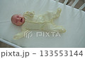 A one-month-old baby lies in a wooden crib, kicking and crying 133553144