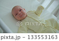 A one-month-old baby lies in a wooden crib, kicking and crying 133553163