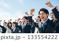 A large group of business people making a fist pump under the blue sky A large group of business people making a fist pump under the blue sky 133554222