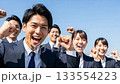 A large group of business people making a fist pump under the blue sky A large group of business people making a fist pump under the blue sky 133554223