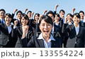 A large group of business people making a fist pump under the blue sky A large group of business people making a fist pump under the blue sky 133554224