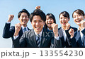 A large group of business people making a fist pump under the blue sky A large group of business people making a fist pump under the blue sky 133554230