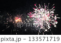 Bright colors explode against the dark sky, illuminating the night with brilliant festive fireworks. Each burst brings joy and excitement to the gathered crowd, celebrating together. 133571719