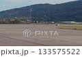Yellow maintenance vehicle inspects airport runway with mountain backdrop 133575522