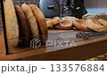 Close-up of a baker removing baked tortillas from a tandoor using special long hooks and serving it on the table. National Georgian bread. 133576884