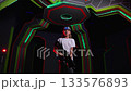 Portrait of a teenage girl with a laser weapon and a marker on her head in a laser tag room, neon stripes on the walls and ceiling. A modern laser tag game area. 133576893