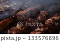 Close-up of juicy meat fried on fire, meat in smoke. Shish kebab on skewers is cooked over hot coals. The concept of cooking meat on the grill. 133576896