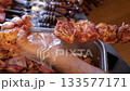 Close-up of a chef wearing gloves stringing marinated pork meat on a skewer in the kitchen of a restaurant or kebab shop. The process of cooking shish kebab. 133577171