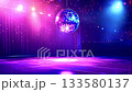 Vibrant mirror ball spinning and reflecting dazzling purple and blue stage lights over an empty dance floor in a nightclub, creating a festive and energetic party atmosphere 133580137