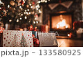 Cozy christmas scene with greeting cards and gifts on a wooden table. A decorated tree with sparkling lights and a warm, burning fireplace create a festive and inviting holiday atmosphere 133580925