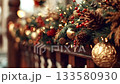 Beautiful festive garland with fir branches, red berries, pine cones, and golden baubles decorating a wooden railing. Warm twinkling lights create a cozy and magical christmas atmosphere 133580930