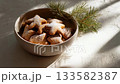A rustic bowl of gingerbread cookie covered with powdered sugar and pine twig decoration on linen fabric in warm natural light 133582387