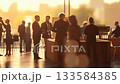 Business people networking and socializing at corporate event during sunset, engaging in professional discussions and building connections in a modern conference space 133584385
