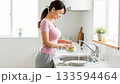 Smiling young woman washing dishes in a bright kitchen 133594464
