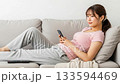 A young woman lying on the sofa and relaxing while using her smartphone 133594469