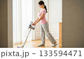 A young woman using a cordless vacuum cleaner in the living room 133594471