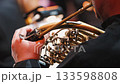 A close-up of a musician's hand gripping a horn, showcasing intricate valves and tubing in a blurred background, highlighting the focus on the instrument and its craftsmanship 133598808