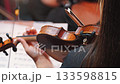 A close-up of a violin in the hands of a musician, demonstrating exquisite skill. The violinist plays the instrument from the rear 133598815