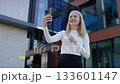 Smiling woman speaking on smartphone video call outdoors 133601147