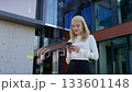 Young woman texting on smartphone outside office building 133601148