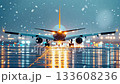 Commercial airplane departing from airport runway during a snowy winter night. Navigating adverse weather conditions with bright lights reflecting on the wet tarmac 133608236