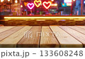 Wooden table at a vibrant bar, creating a romantic atmosphere for date night with glowing neon heart lights and bokeh background, representing love and nightlife concepts 133608248