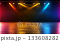Empty stage illuminated by colorful spotlights casting vibrant light beams and reflections onto the textured concrete floor, creating a dynamic backdrop for events 133608282