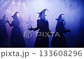 Witches in silhouette with pointed hats and robes, performing a smoky, theatrical ritual dance under vivid purple and blue stage lights, evoking mystical, spooky energy 133608296