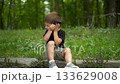 Three year old child sitting on curb in park talking on phone 4k 133629008