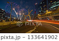 Long exposure time-lapse of traffic light trails on an overpass with fireworks exploding over a bridge and city skyline at night. Long exposure time-lapse of traffic light trails on an overpass with fireworks exploding over a bridge and city skyline at night. 133641902