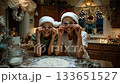 A woman and a boy in santa hats are making cookies together 133651527