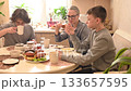 A middle-aged Caucasian woman has dinner with her two sons.  133657595