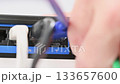 A woman pulls a cable out of an internet port on a router.  133657600