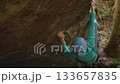 slow motion woman climber climbs crag bouldering reaching holds and making hard movements showing strength and power. healthy sport lifestyle, active leisure. rock climbing outdoors in autumn forest. 133657835