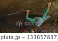 slow motion woman climber climbs crag bouldering reaching holds and making hard movements showing strength and power. healthy sport lifestyle, active leisure. rock climbing outdoors in autumn forest. 133657837
