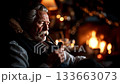 A man sitting in front of a fireplace smoking a pipe 133663073
