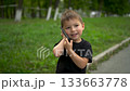 Three year old child walking in park talking on phone closeup. 4k 133663778