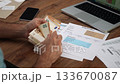 Following utility bills receipt male accountant sitting at table unfolds banknotes in hands counting euros, man calculates total amount of expenses slow motion 133670087