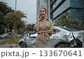 Woman standing near a damaged car while talking on the phone in an urban area during daylight 133670641